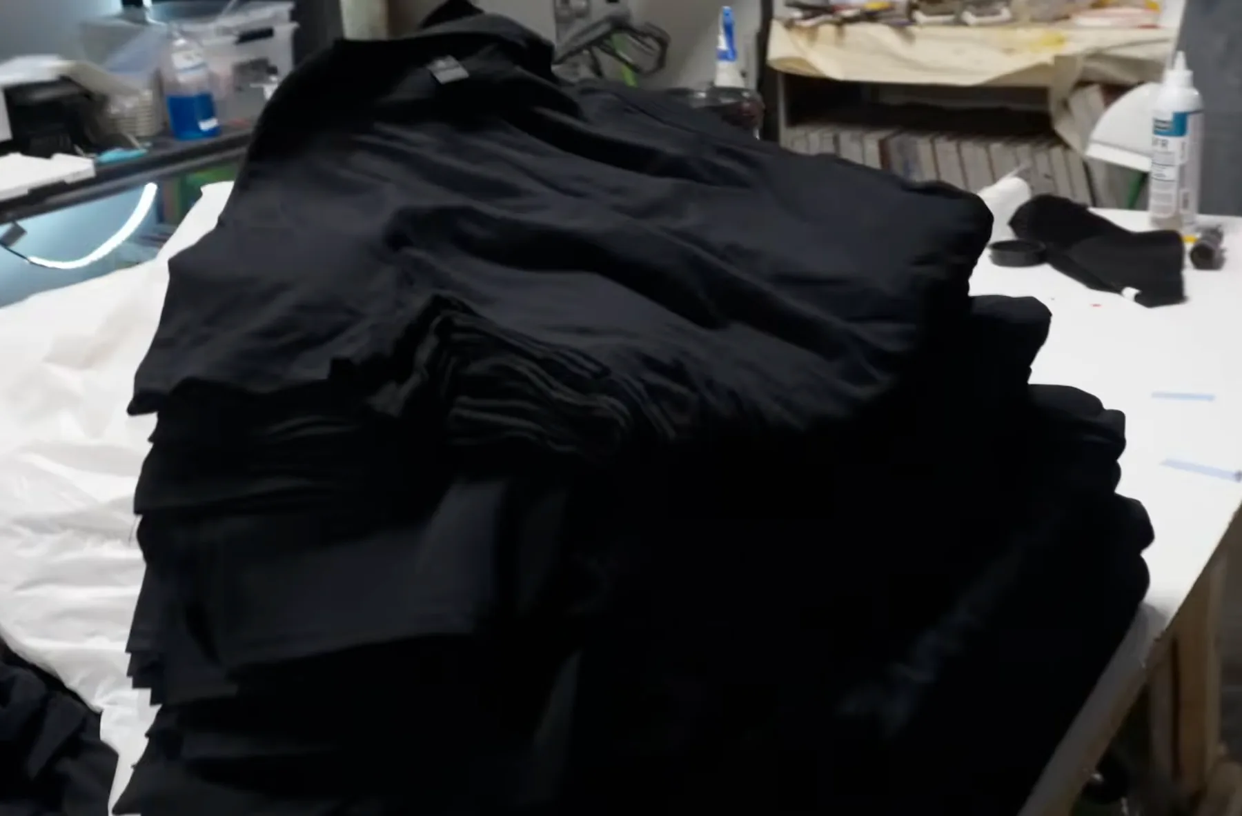 Stack of black DryBlend shirts on an AMS shop table during a fast-turnaround apparel production run